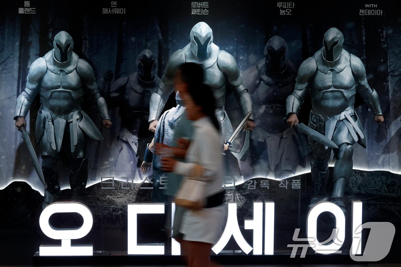 본문 이미지 - 영화 '오디세이'(감독 크리스토퍼 놀런)가 개봉 12일째에 400만 관객을 돌파한 16일 서울 시내 한 대형 쇼핑몰 내 영화관을 찾은 관람객이 영화 '오디세이' 홍보물 앞을 지나고 있다. 2026.8.16 ⓒ 뉴스1 박정호 기자