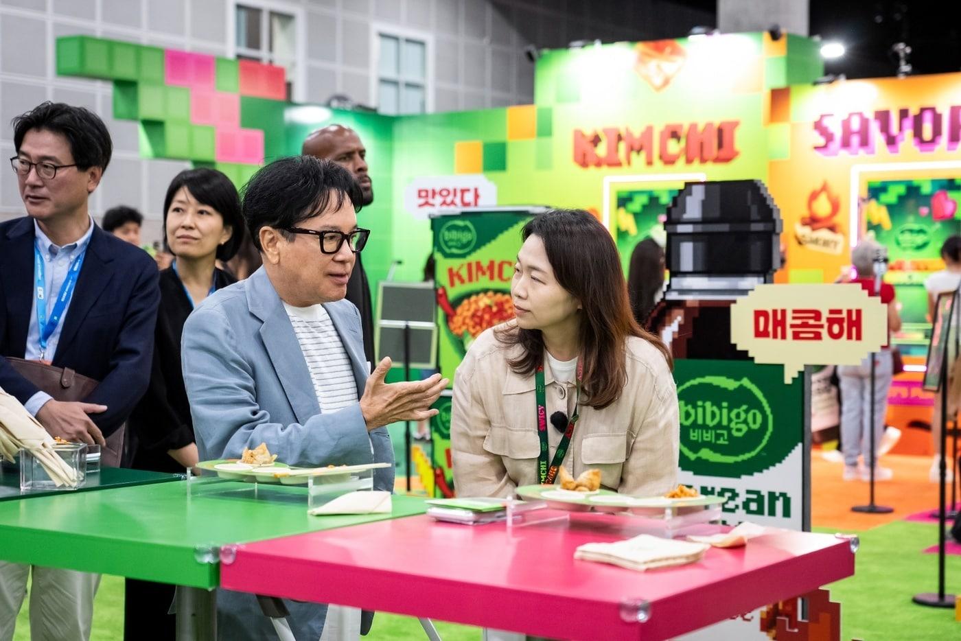 본문 이미지 - K콘 LA 2026을 방문한 이재현 CJ 회장이 비비고 부스에서 미니완탕과 김치 라면을 맛보고 있다.(CJ그룹 제공)