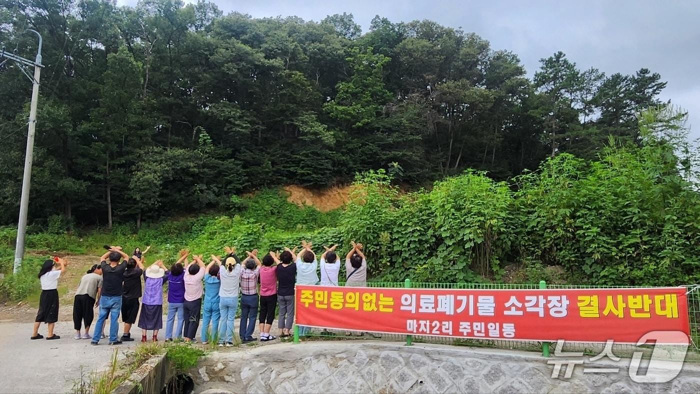 본문 이미지 - 파주시 적성면 주민들이 의료폐기물 소각장 건립 예정부지 현장에서 건립 반대 의사로 손으로 ‘X’ 표시를 하는 퍼포먼스를 하고 있다. (독자 제공, 재판매 및 DB금지)