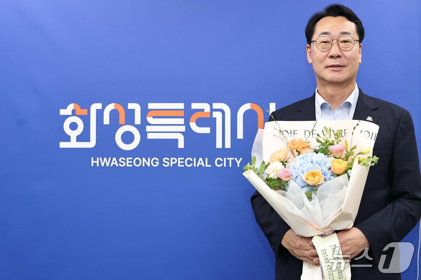 본문 이미지 - 정명근 화성특례시장이 대한민국대도시시장협의회 제23대 회장으로 선출된 뒤 축하 꽃다발을 들고 기념촬영을 하고 있다.(화성시 제공)