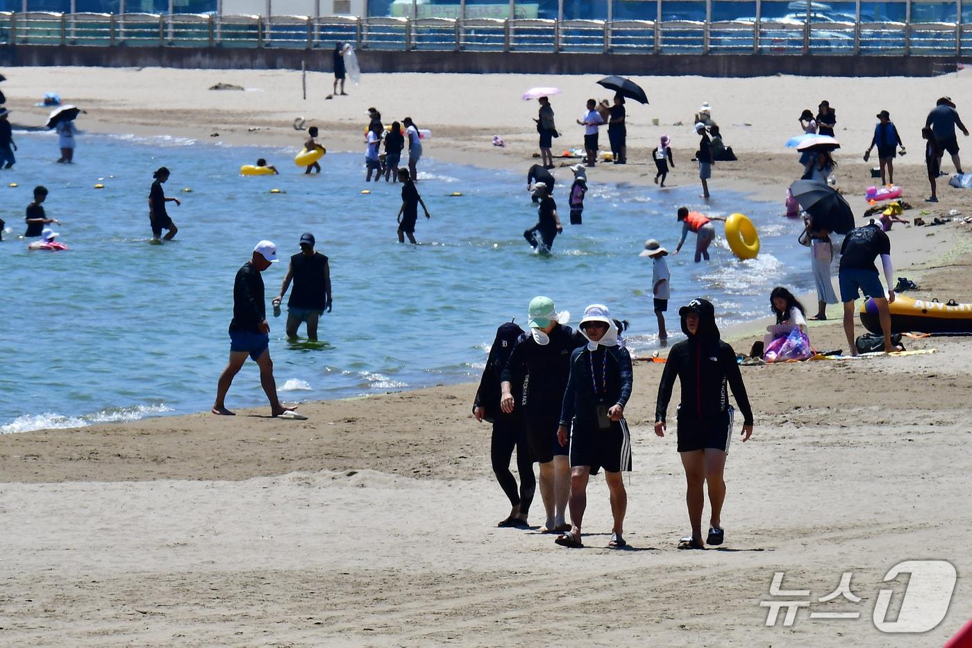 본문 이미지 - 2일 경북 포항시 북구 영일대해수욕장 백사장에서 피서객들이 모자 등으로 얼굴을 가린채 걸어가고 있다.  2026.8.2 ⓒ 뉴스1 최창호 기자