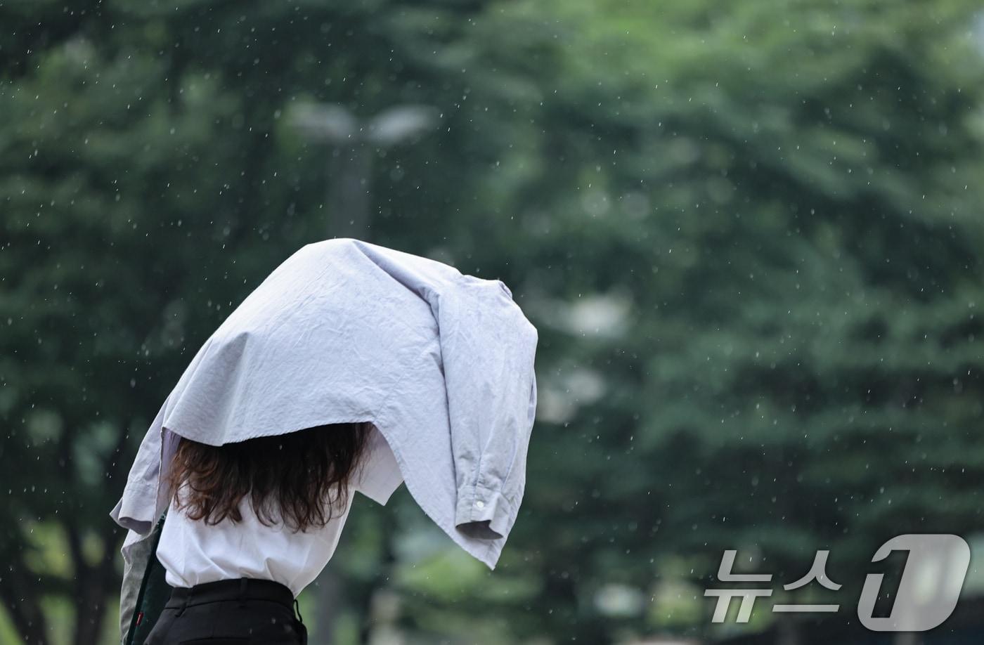 본문 이미지 - 20일 서울 종로구 종각역 인근에서 한 시민이 겉옷을 우산삼아 길을 지나고 있다. 2026.8.20 ⓒ 뉴스1 김도우 기자