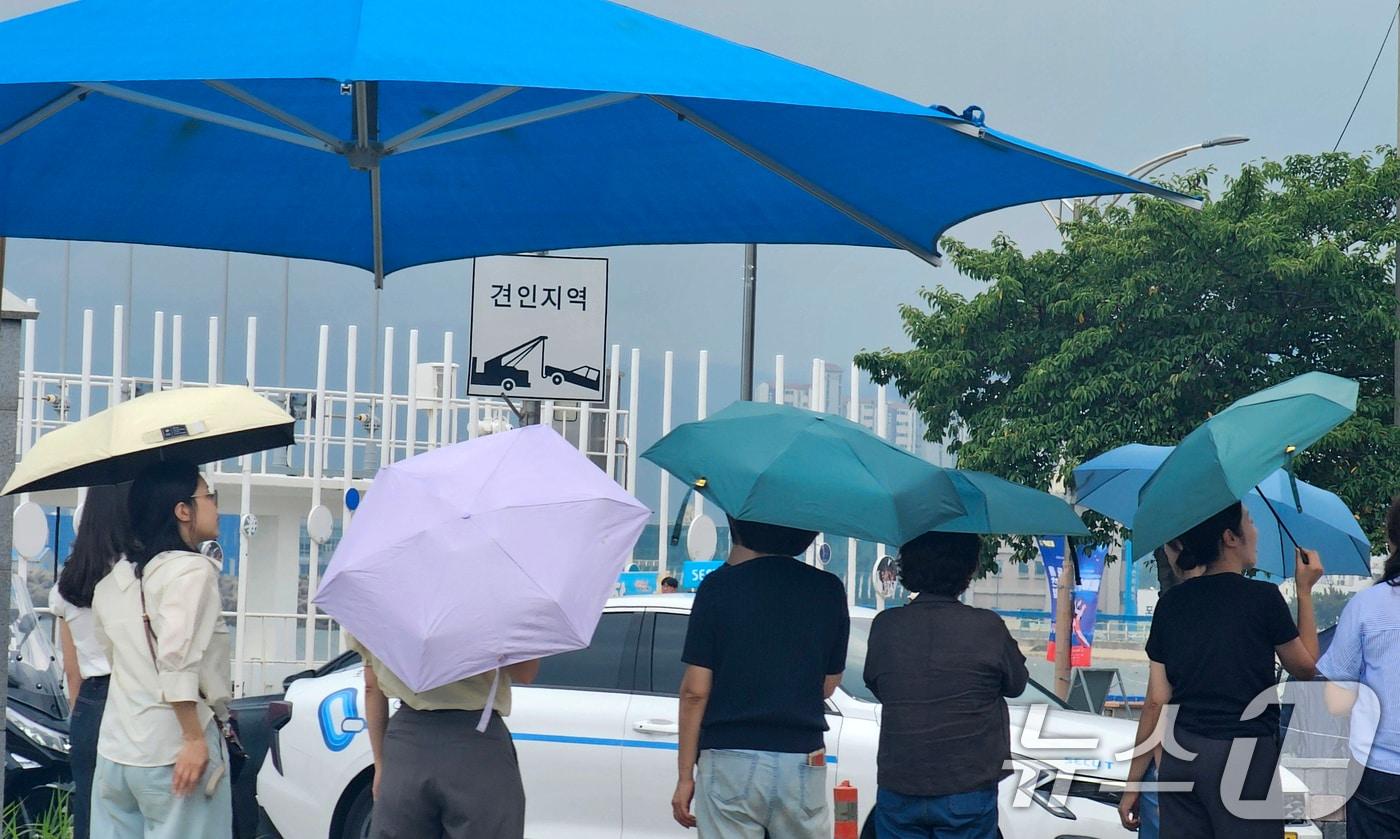 본문 이미지 - 21일 오후 경북 포항시 북구 영일대해수욕장 인근 횡단보도에서 우양산을 쓴 시민들이 신호를 보행자 신호를 기다리고 있다. 2026.8.21 ⓒ 뉴스1 최창호 기자