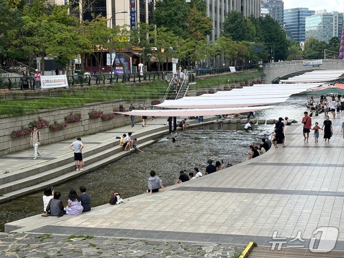 본문 이미지 - 절기상 더위가 그친다는 처서(處暑)인 23일 오후 서울 종로구 청계천을 찾은 시민들이 대형 그늘막 아래에서 더위를 식히고 있다. 2026.8.23/뉴스1 ⓒ 뉴스1 소봄이 기자