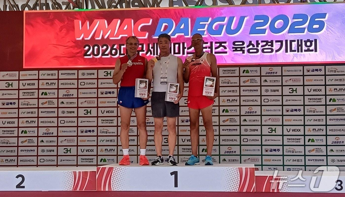 본문 이미지 - 2026 대구세계마스터즈육상경기대회 장대높이뛰기에 출전해 대한민국 첫 금메달을 수상한 김철균 선수(가운데)가 시상대에 올라 있다. (대구시 제공. 재판매 및 DB 금지)/뉴스1