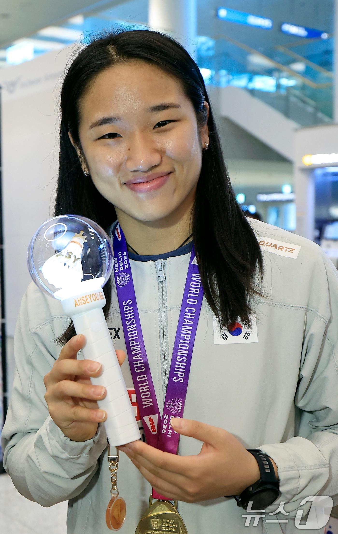 본문 이미지 - 2026 세계배드민턴연맹(BWF) 세계선수권대회 여자 단식을 제패한 안세영이 25일 오전 인천국제공항을 통해 귀국, 팬카페 회원들이 제작해 선물한 자신의 응원봉을 들어 보이고 있다. 세계랭킹 1위 안세영은 지난 23일(한국시간) 인도 뉴델리에서 열린 2026 세계배드민턴연맹(BWF) 세계선수권대회 여자단식 결승에서 야마구치 아카네(2위·일본)를 49분 만에 게임 스코어 2-0(21-17 21-14)으로 제압하며 지난 2023년 우승 이후 3년 만에 다시 세계선수권 정상에 올랐다. ⓒ 뉴스1 박정호 기자