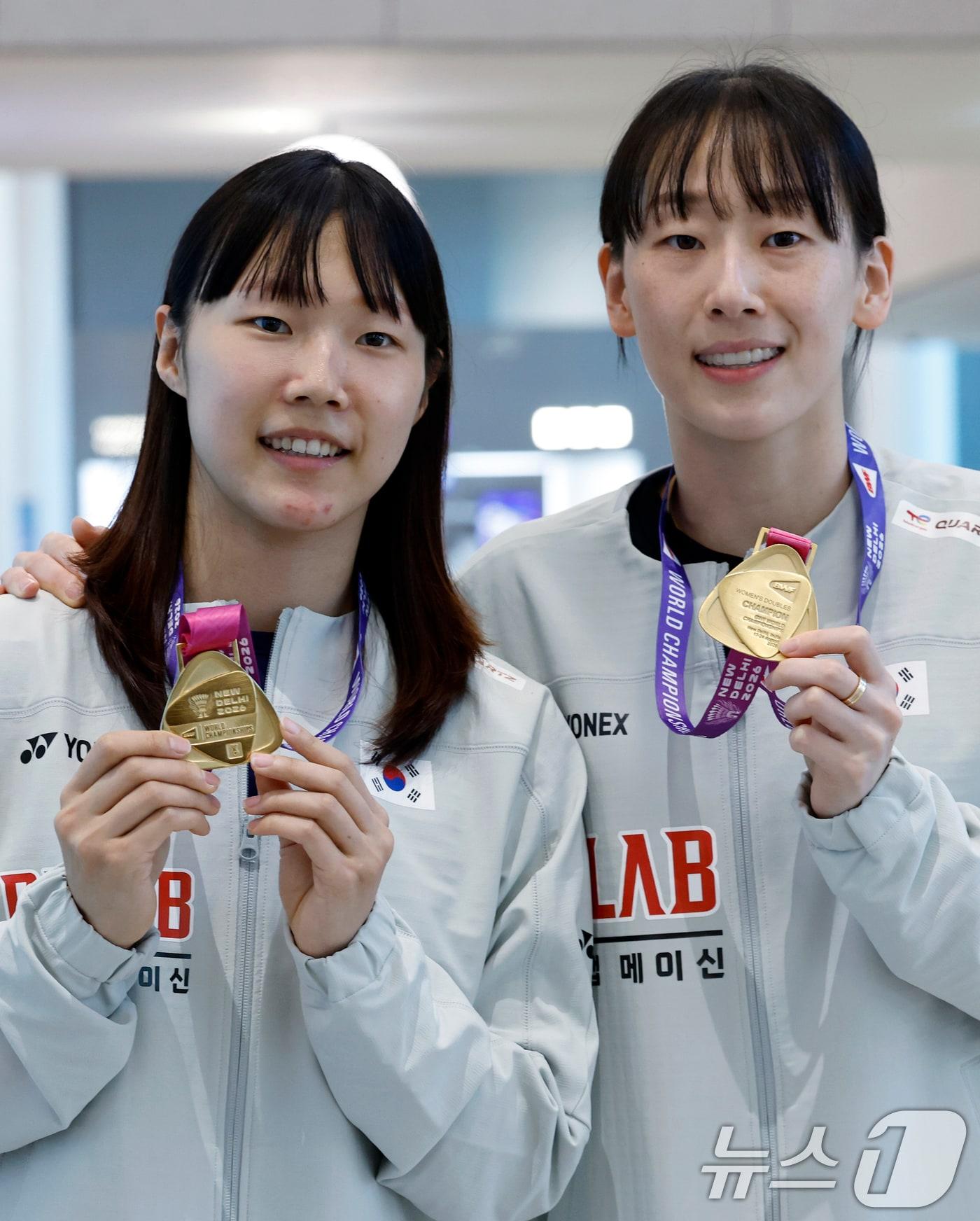 본문 이미지 - 세계선수권대회 여자복식 우승을 차지한 이소희(오른쪽)와 백하나가 25일 오전 인천국제공항을 통해 귀국해 메달을 들어 보이고 있다.  ⓒ 뉴스1 박정호 기자