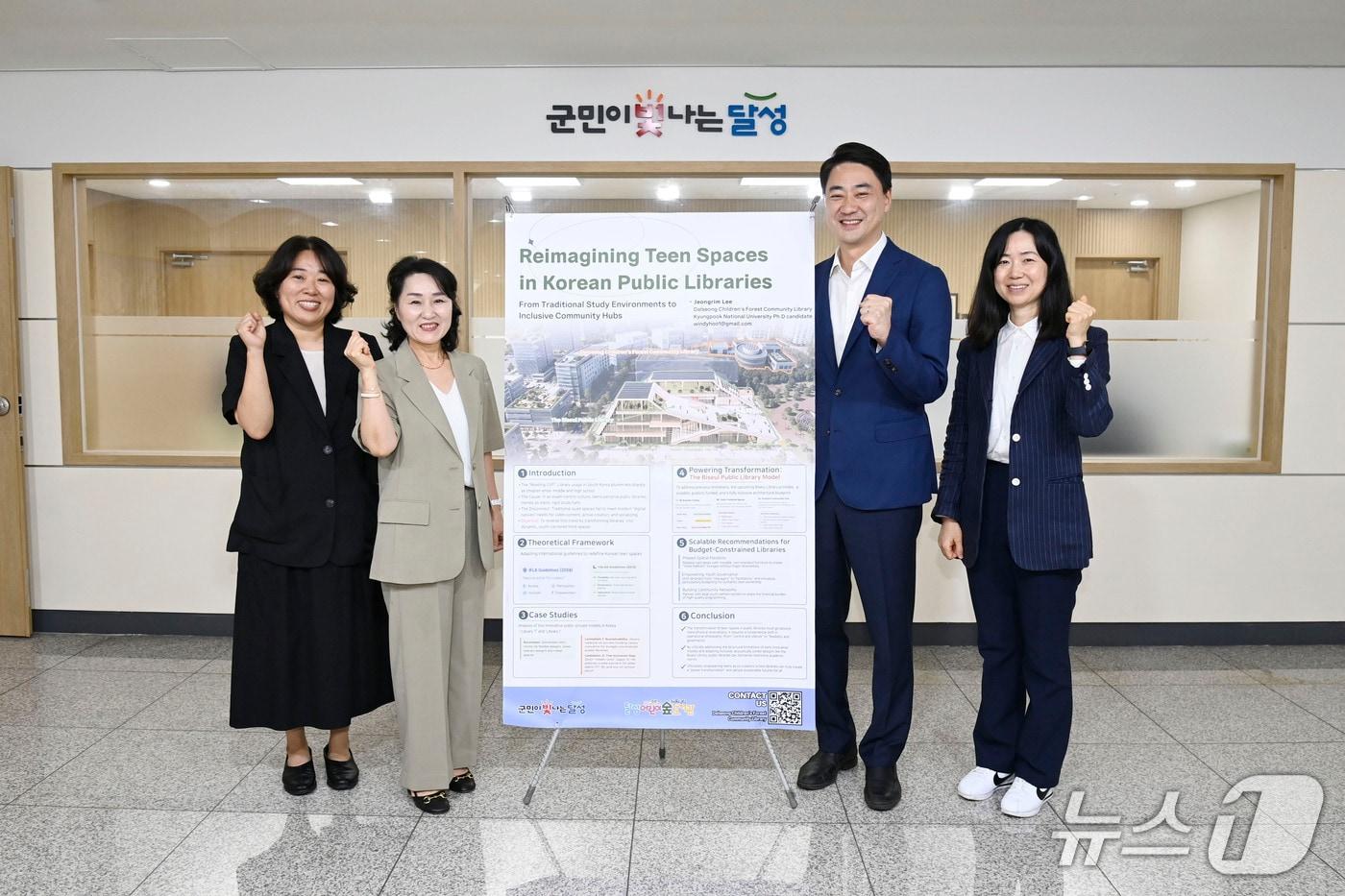 본문 이미지 - 대구 달성군 관계자들이 90회 국제도서관협회연맹(IFLA) 세계도서관정보대회에서 발표할 '한국 공공도서관의 청소년 공간 재구성' 자료 앞에서 기념촬영을 하고 있다.(대구 달성군 제공. 재판매 및 DB금지)