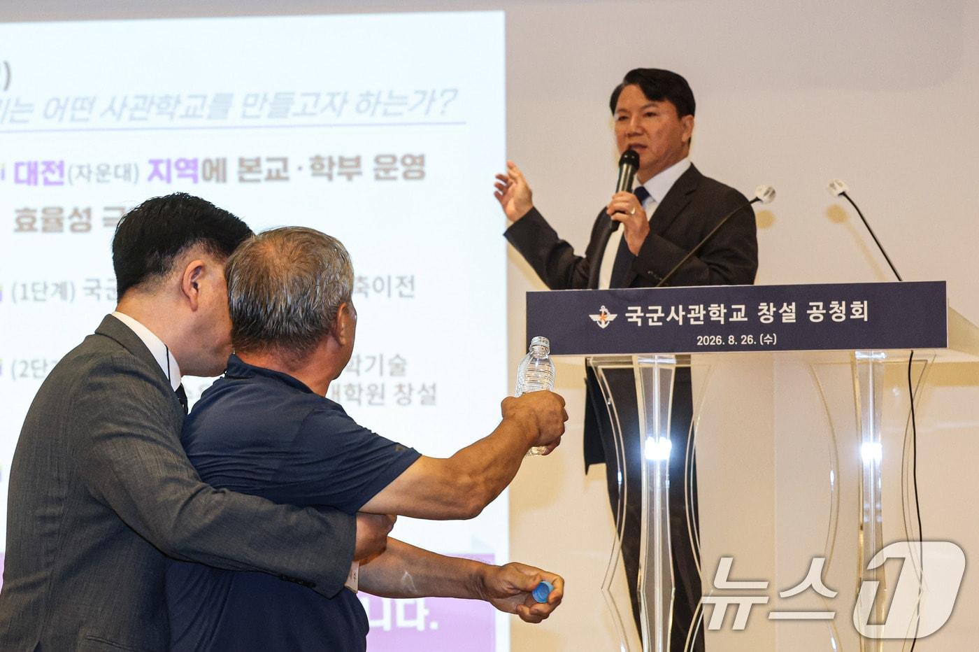 본문 이미지 - 26일 오후 서울 용산구 국방컨벤션에서 열린 국군사관학교 창설 공청회에서 한 참석자가 발언하고 있는 김홍철 국방부 정책실장에게 생수병을 든 채 다가서고 있다. (공동취재) 2026.8.26 ⓒ 뉴스1 최지환 기자