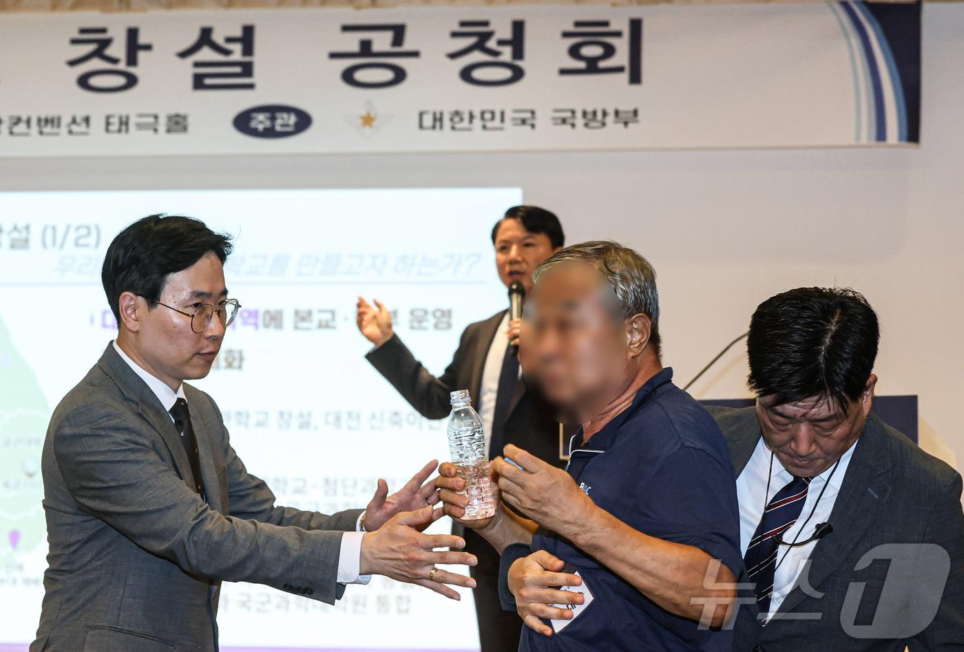 본문 이미지 - 26일 오후 서울 용산구 국방컨벤션에서 열린 국군사관학교 창설 공청회에서 한 참석자가 발언하고 있는 김홍철 국방부 정책실장에게 생수병을 든 채 다가서고 있다. (공동취재) 2026.8.26 ⓒ 뉴스1 최지환 기자