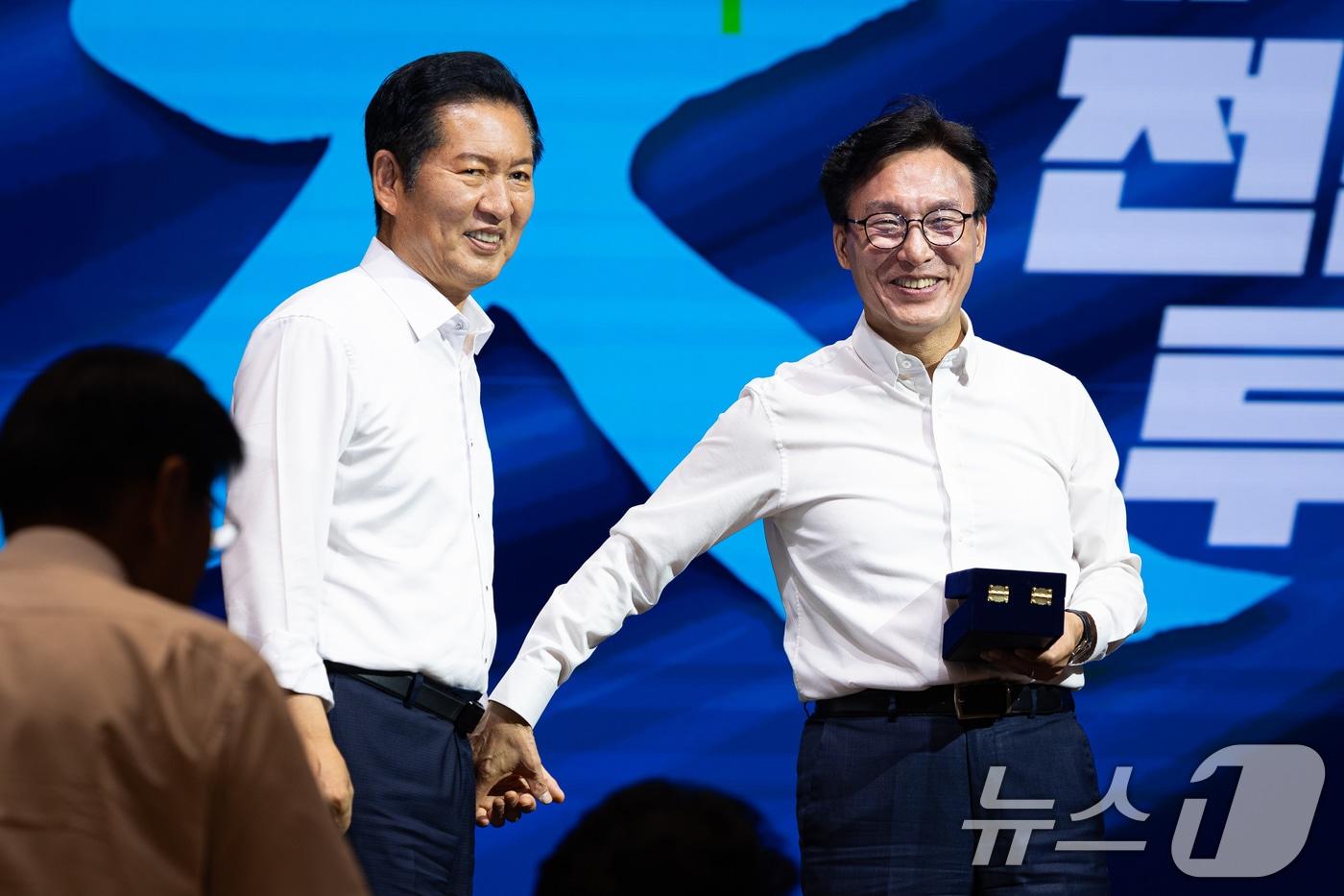 본문 이미지 - 김민석 더불어민주당 대표가 27일 인천 영종구 인스파이어 엔터테인먼트 리조트에서 열린 2026년 정기국회 대비 국회의원 워크숍에서 정청래 전 대표에게 감사패 전달에 앞서 손을 잡고 있다. 2026.8.27 ⓒ 뉴스1 유승관 기자
