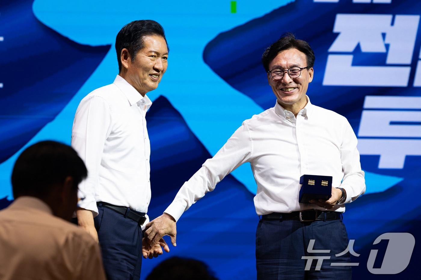 본문 이미지 - 김민석 더불어민주당 대표가 27일 인천 영종구 인스파이어 엔터테인먼트 리조트에서 열린 2026년 정기국회 대비 국회의원 워크숍에서 정청래 전 대표에게 감사패 전달에 앞서 손을 잡고 있다. 2026.8.27 ⓒ 뉴스1 유승관 기자