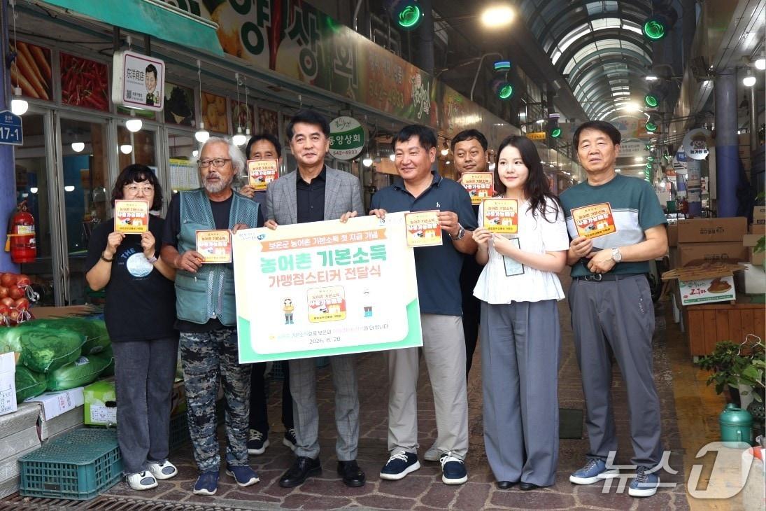 본문 이미지 - 최재형 보은군수가 28일 농어촌 기본소득 첫 지급을 기념하는 가맹점스티커를 전달하고 있다.(보은군 제공. 재판매 및 DB금지)/뉴스1  