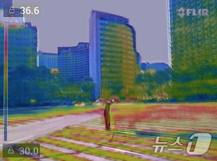 본문 이미지 - 전국에 폭염 특보가 내려진 3일 서울시 관계자가 서울광장 잔디에 물을 뿌리고 있는 장면을 열화상 카메라로 촬영해 레이어 합성했다. 물을 뿌리는 부분은 비교적 온도가 낮아 파랗게 보이고 주변은 금방 다시 데워져 붉은색으로 나타나고 있다. 2026.8.3 ⓒ 뉴스1 구윤성 기자