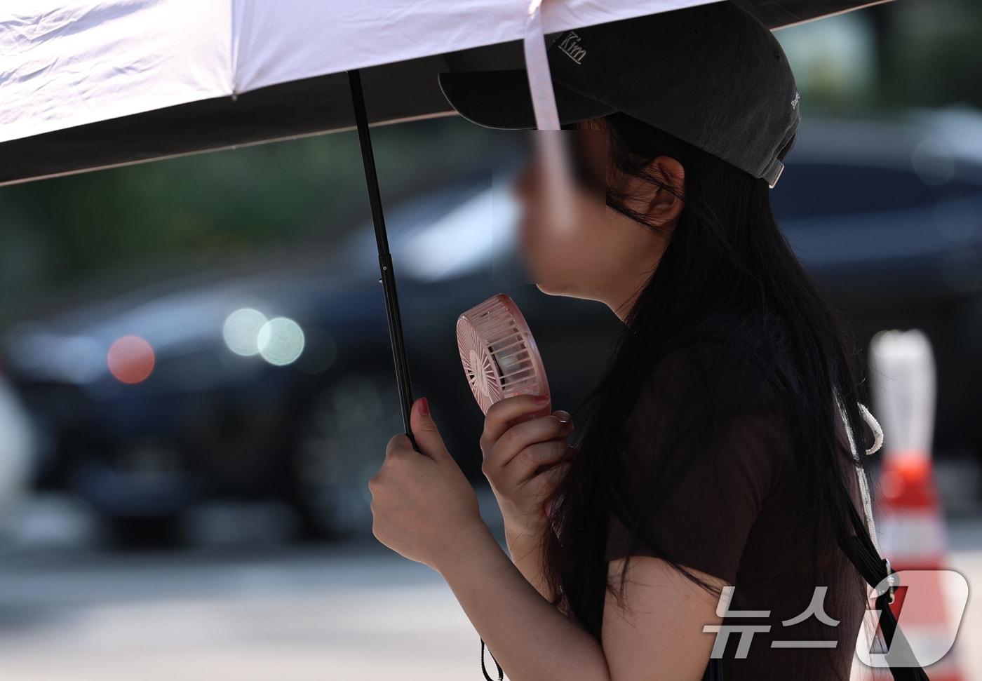 본문 이미지 - 강원 일부 지역을 제외한 전국에 폭염특보가 내려진 3일 오전 서울 광화문 네거리에서 한 시민이 양산과 휴대용 선풍기로 더위를 식히고 있다. 2026.8.3 ⓒ 뉴스1 구윤성 기자