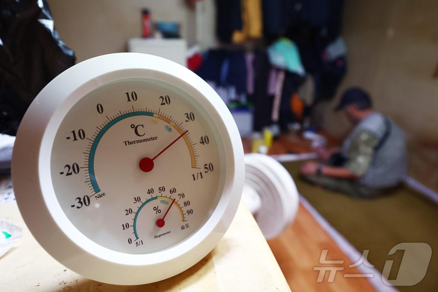 본문 이미지 - 서울 최고 기온이 37도까지 오르는 등 기록적인 폭염이 이어지고 있는 3일 서울의 한 쪽방촌에서 어르신이 선풍기 한 대에 의지해 더위를 식히고 있다. 사진 왼쪽 온도계는 35도 가까이를 가리키고 있다. 2026.8.3 ⓒ 뉴스1 김민지 기자