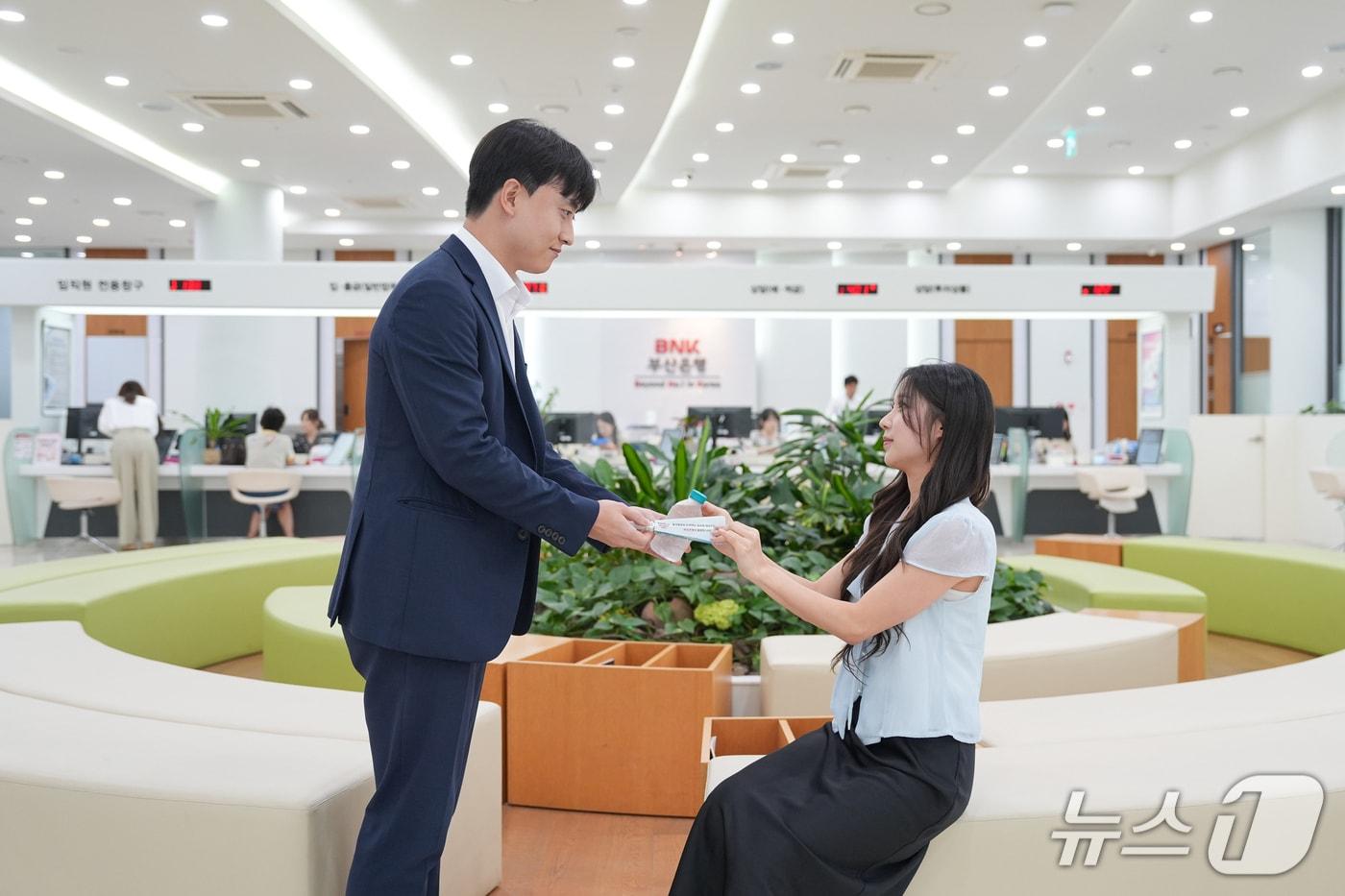 본문 이미지 - 우리동네 기후쉼터로 운영되는 한 부산은행 영업점을 찾은 고객에 생수 등을 전달하는 모습 (BNK금융 제공. 재판매 및 DB금지)