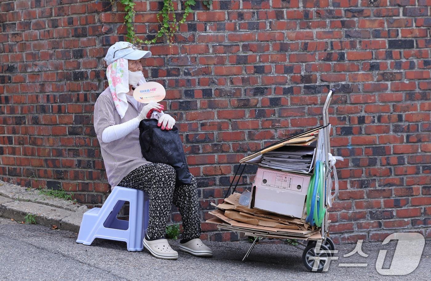 본문 이미지 - 4일 서울 용산구 효창동 일대 골목에서 폐지를 수집하는 노인이 서울시에서 지급한 폭염 예방 물품으로 더위를 식히고 있다. 2026.8.4 ⓒ 뉴스1 박지혜 기자
