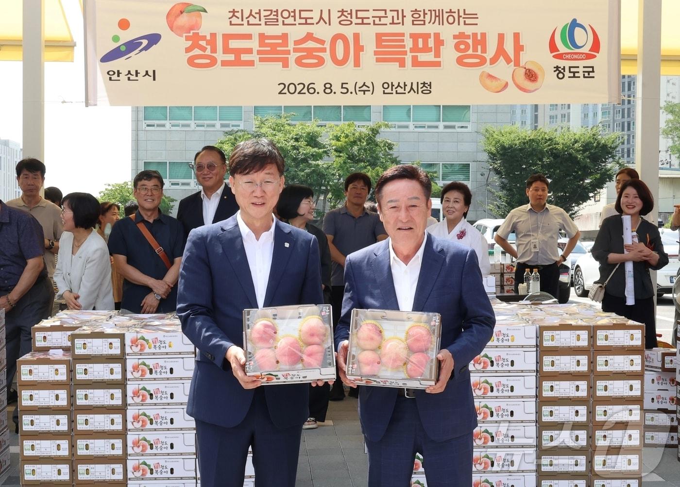 본문 이미지 - 자매도시 경기 안산시에서 청도복숭아 특판행사를 연 박권현 경북 청도군수(오른쪽)가 5일 이민근 안산시장과 청도복숭아를 들고 기념사진을 찍고 있다.(청도군 제공. 재판매 및 DB금지)2026.8.5 ⓒ 뉴스1 정우용 기자