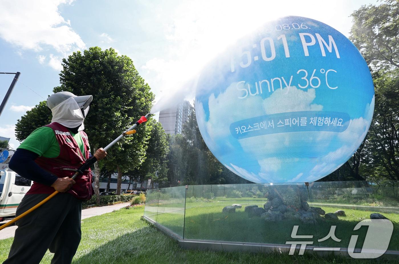 본문 이미지 - 전국에 극한폭염이 계속되는 가운데 6일 서울 송파구 석촌호수에 위치한 미디어아트 조형물 '더 스피어' 앞에서 구청 관계자가 지면 온도를 낮추기 위해 물을 뿌리고 있다. 2026.8.6 ⓒ 뉴스1 최지환 기자