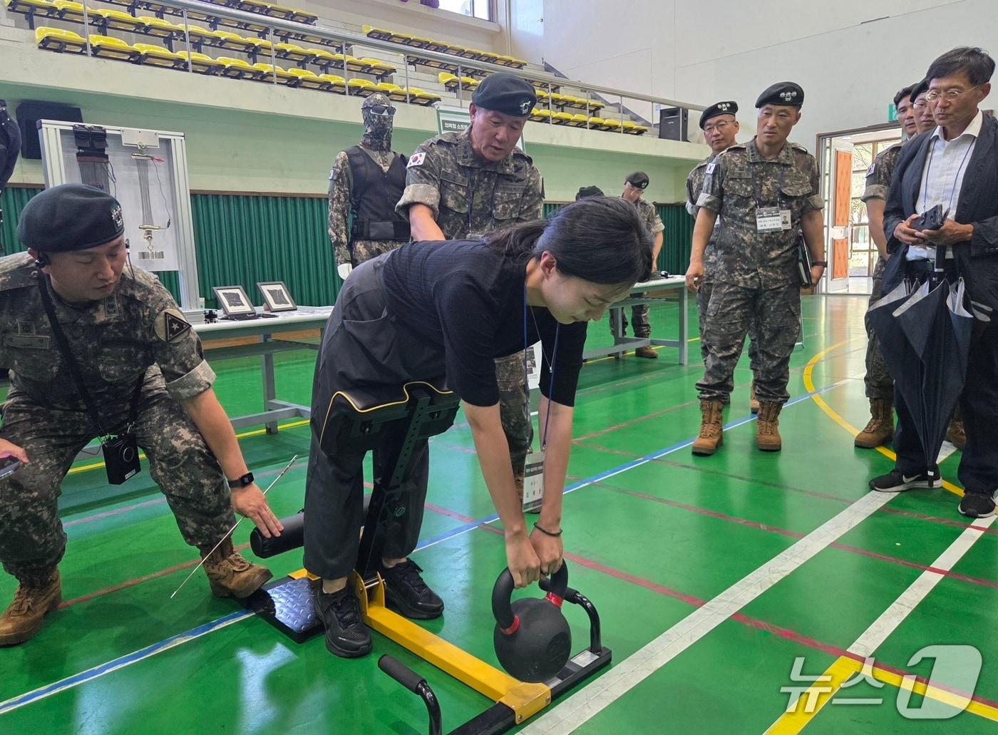 본문 이미지 - 7일 육군 제1보급단 스마트 물류센터 야외전시장에서 기자가 직접 웨어러블 로봇을 입고 20kg 케틀벨을 들어올리고 있다.  ⓒ 뉴스1 김예원 기자