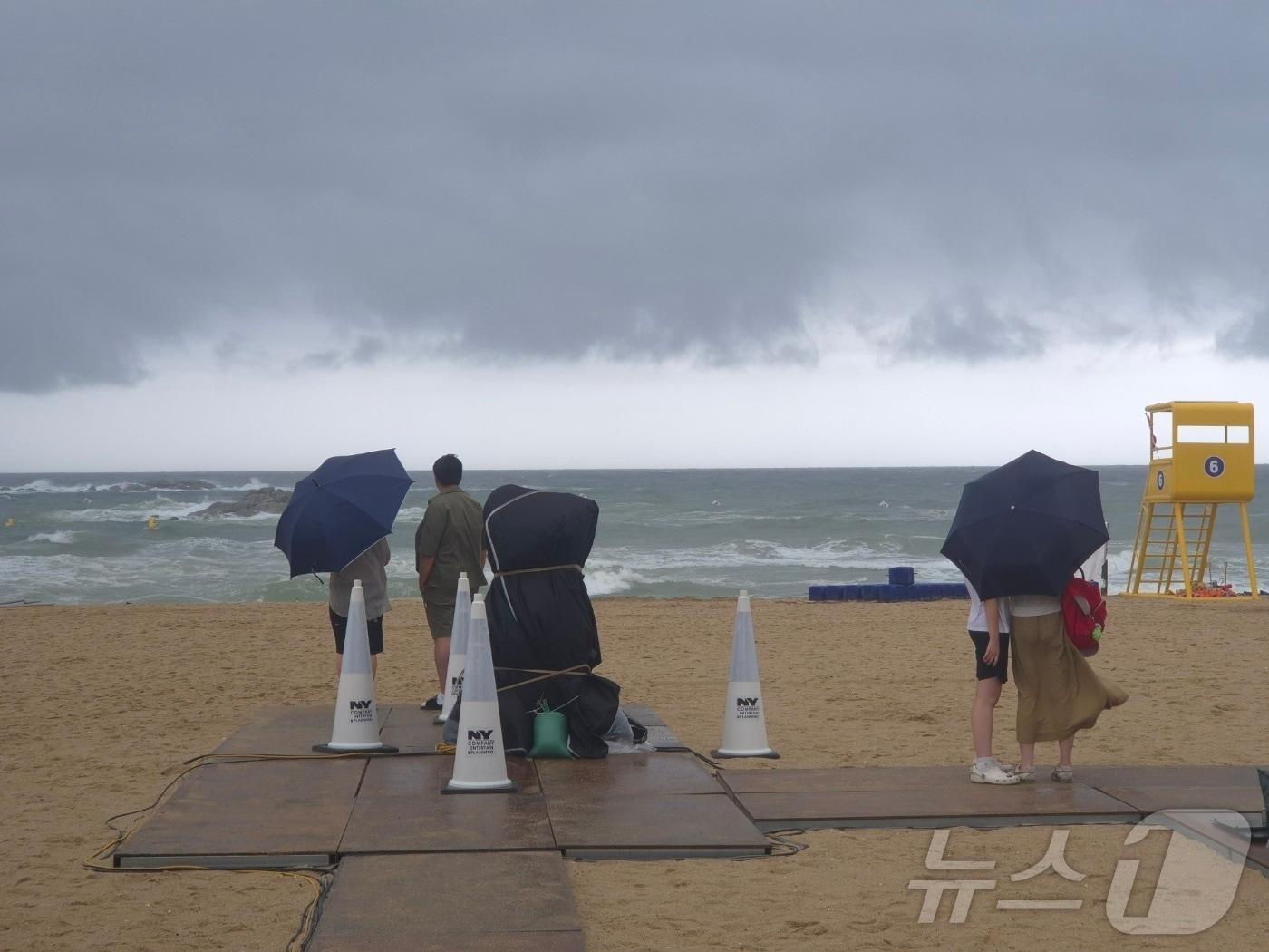 본문 이미지 - 강원 동해안과 산지를 중심으로 호우특보가 발효된 8일 강릉시 경포해수욕장을 찾은 피서객들이 우산을 쓴 채 거센 파도가 이는 바다를 바라보고 있다. 이날 강릉지역에는 오후 1시까지 도마 87.5㎜, 연곡 67.0㎜, 북강릉 62.5㎜의 비가 내렸으며, 동해안과 산지를 중심으로 호우특보가 발효됐다. 2026.8.8 ⓒ 뉴스1 윤왕근 기자