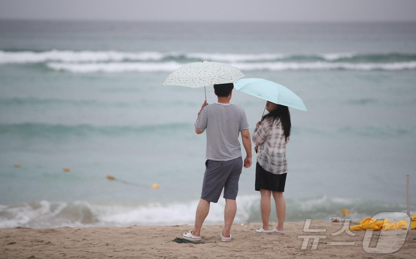 본문 이미지 - 제주시 조천읍 함덕해수욕장에서 우산을 쓴 관광객들이 파도가 이는 바다를 바라보고 있다. 2026.8.9 ⓒ 뉴스1 강승남 기자