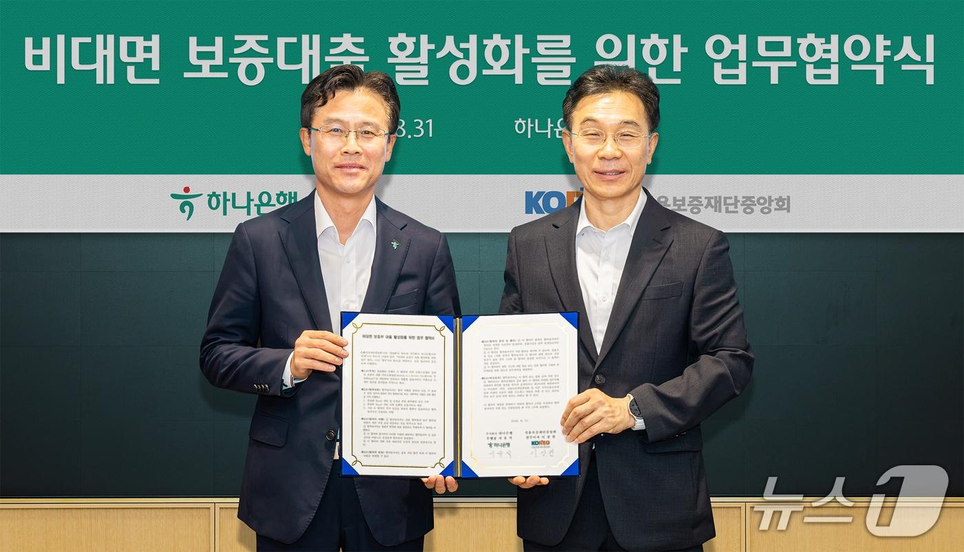 본문 이미지 - 하나은행은 31일 오후 하나은행 을지로 본점에서 '비대면 보증부 대출 활성화를 위한 업무협약'을 체결했다. 이날 협약식에 참석한 서유석 하나은행 기업그룹 부행장(사진 왼쪽)이 이상천 신용보증재단중앙회 전무이사(사진 오른쪽)와 함께 협약서를 들고 기념촬영을 하고 있다. 2026.08.31 / 사진제공=하나은행
