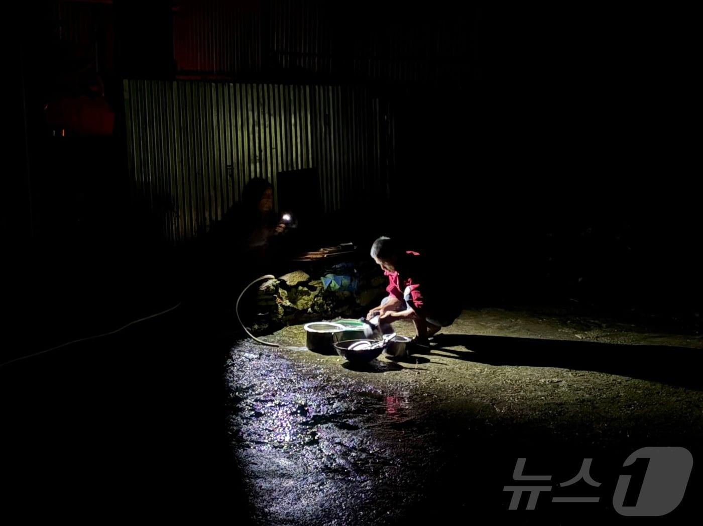 본문 이미지 - 지난 31일(현지시간) 정부합동신속대응팀이 머물고 있는 네팔 라수와 지역 람체에서 마을 주민들이 휴대폰 불빛에 의지해 설거지를 하고 있다. 람체는 비교적 고지대에 위치해 직접적인 홍수와 산사태 피해는 없었지만 전기가 끊겨 소형 발전기를 돌려 제한적으로 이용하고 있다. 2026.9.1 ⓒ 뉴스1 구윤성 기자