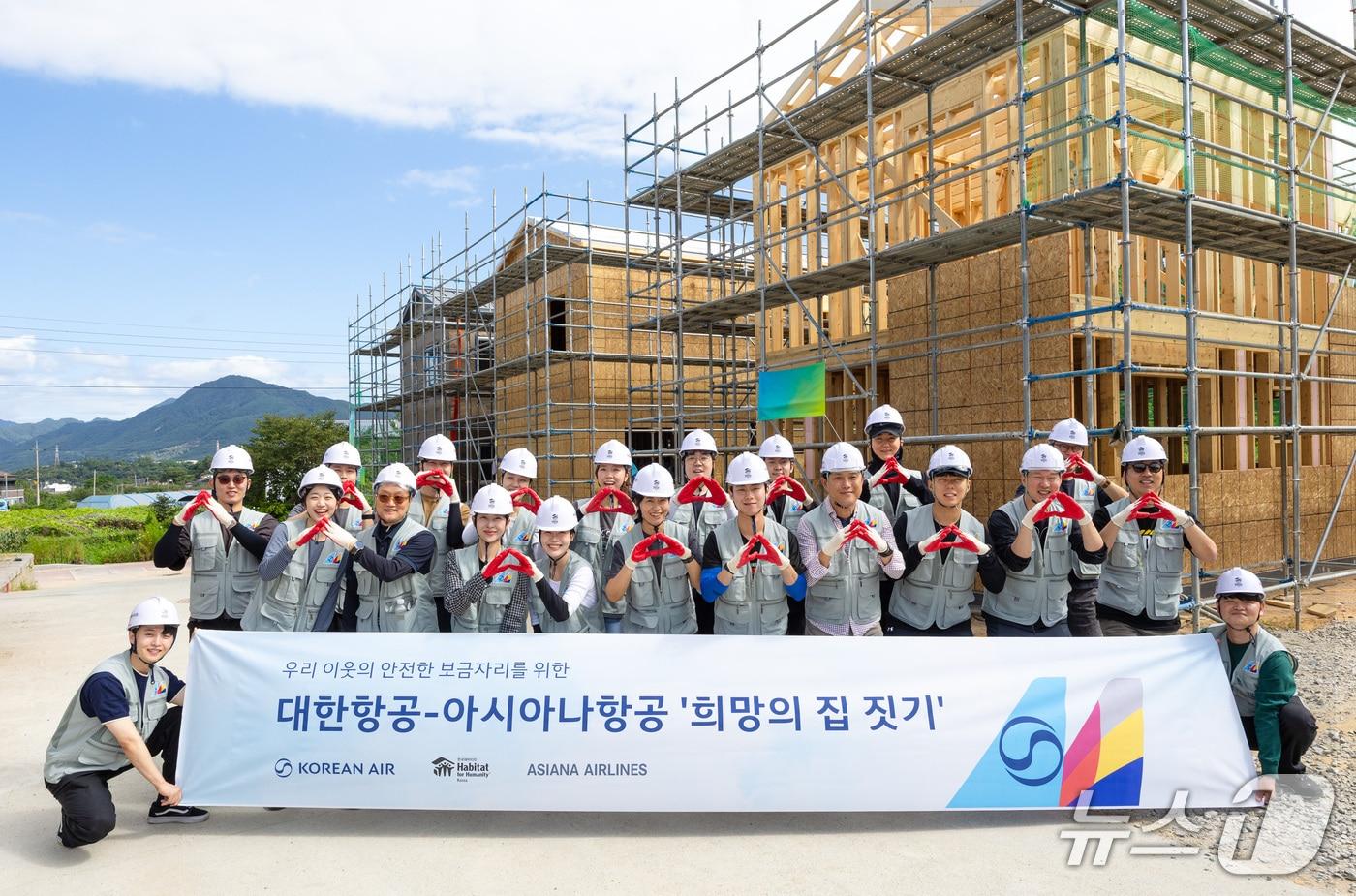 본문 이미지 -  지난 9일 강원도 춘천시에서 진행된 한국해비타트 '희망의 집 짓기' 봉사활동에 참여한 대한항공, 아시아나항공 임직원들이 기념사진을 촬영하고 있다.(대한항공 제공)