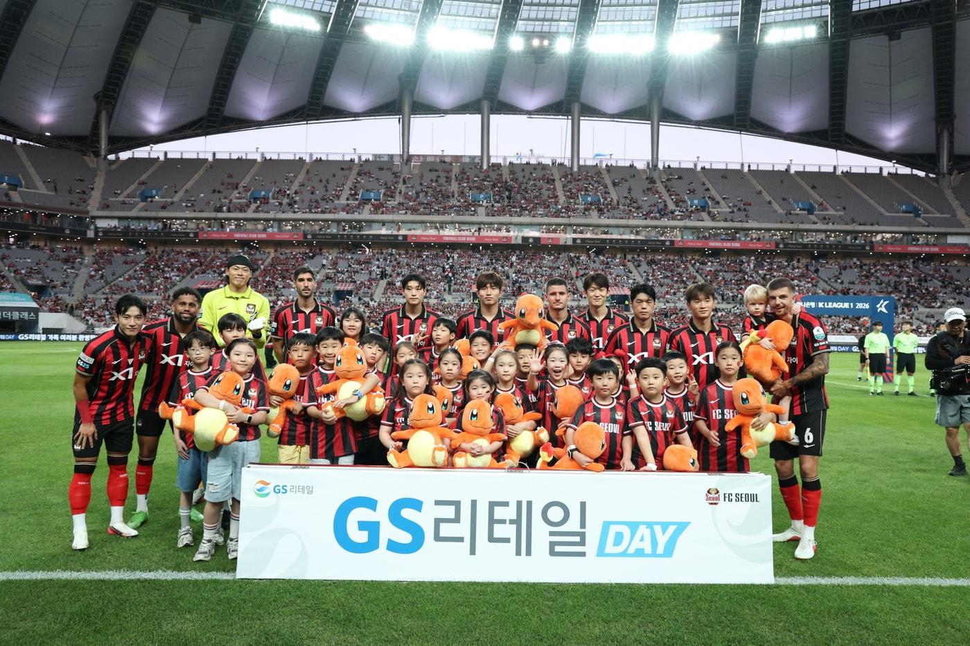 본문 이미지 - GS리테일 브랜드 데이 행사에 참석한 임직원 자녀들이 경기에 앞서 FC서울 선수들과 기념 촬영을 하고 있다.(GS리테일 제공)