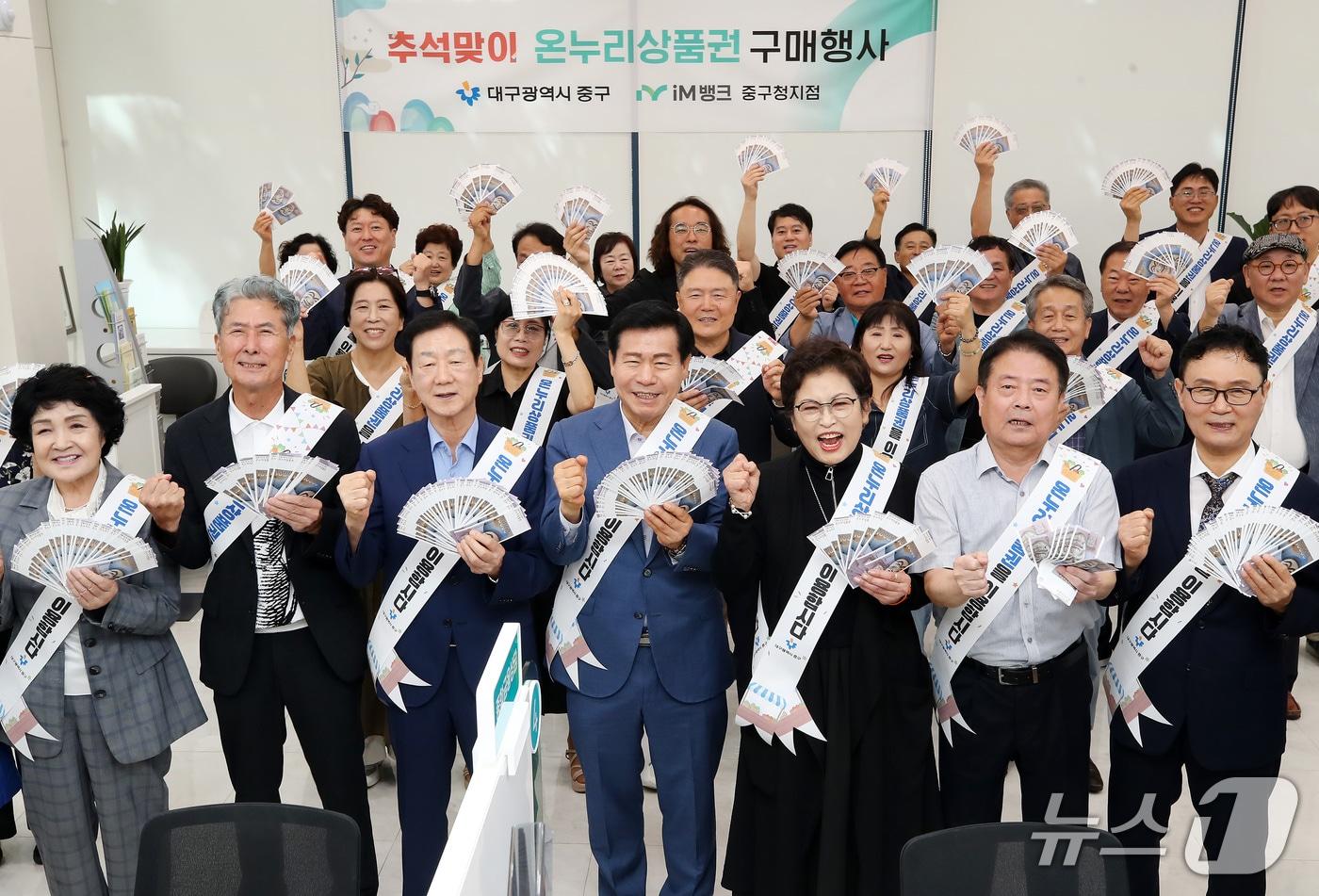 본문 이미지 - 14일 대구 중구 iM뱅크 중구청지점에서 열린 '2026년 추석맞이 온누리상품권 구매 행사'에서 류규하 중구청장, 유성자 중구의회 의장, 임인환 대구시의회 의장, 서문시장상인회, 중구 주민, 중구청 직원 등 참석자들이 전통시장 활성화를 위해 구매한 온누리상품권을 펼쳐 보이고 있다. 2026.9.14 ⓒ 뉴스1 공정식 기자