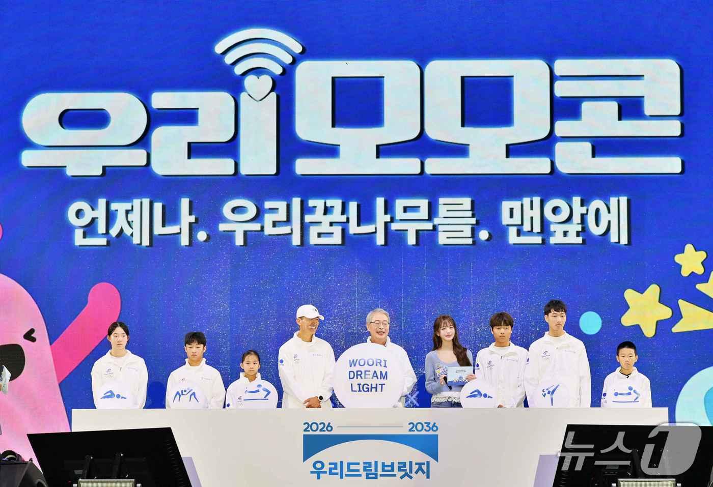 본문 이미지 - 지난 19일 과천 서울랜드에서 열린 '2026 우리 모모콘'에서 우리금융그룹 임종룡 회장(왼쪽 다섯번째)과 우리은행 앰배서더 장원영(오른쪽 네번째), 가수 션(왼쪽 네번째) 등이 ‘우리드림브릿지’ 후원 선수들과 함께 '우리드림브릿지' 스포츠 사회공헌 사업을 선포 하고 있다. 2026.09.19 / 사진제공=우리금융그룹