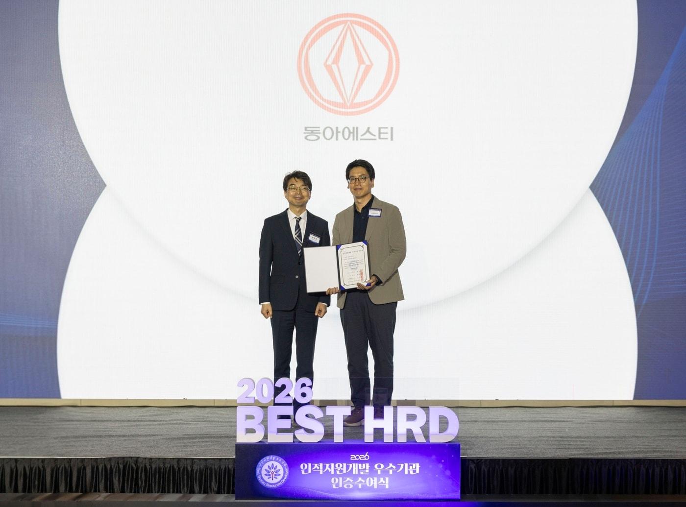 본문 이미지 - 2026년 인적자원개발 우수기업(Best HRD) 인증수여식에서 김범석 동아에스티 행복경영실 인사팀장(오른쪽)과 편도인 고용노동부 직업능력정책국장(왼쪽)이 기념사진을 촬영하고 있다. (동아에스티 제공)