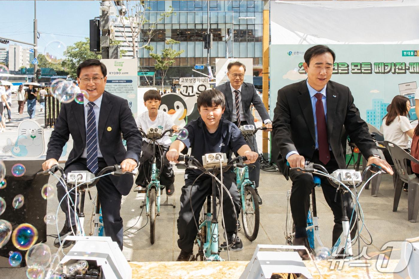 본문 이미지 - 지난 21일 서울 종로구 광화문광장에서 열린 ‘제4회 지구하다 페스티벌’에서 김성환 기후에너지환경부 장관(왼쪽)과 조대규 교보생명 대표이사 사장이 자전거 발전기 체험을 하고 있다./사진제공=교보생명