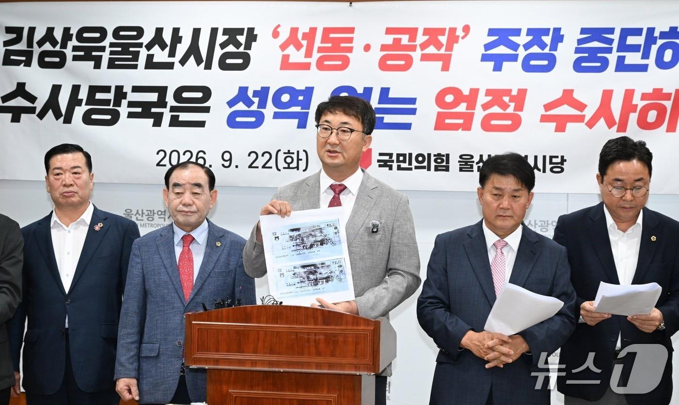 본문 이미지 - 김상회 국민의힘 울산시당위원장 직무대행(가운데)이 22일 시의회 프레스센터에서 기자회견을 열고 김상욱 울산시장의 의혹 제기 이후 전달된 수표의 사진을 들어보이고 있다.(울산시의회 제공. 재판매 및 DB 금지)/뉴스1