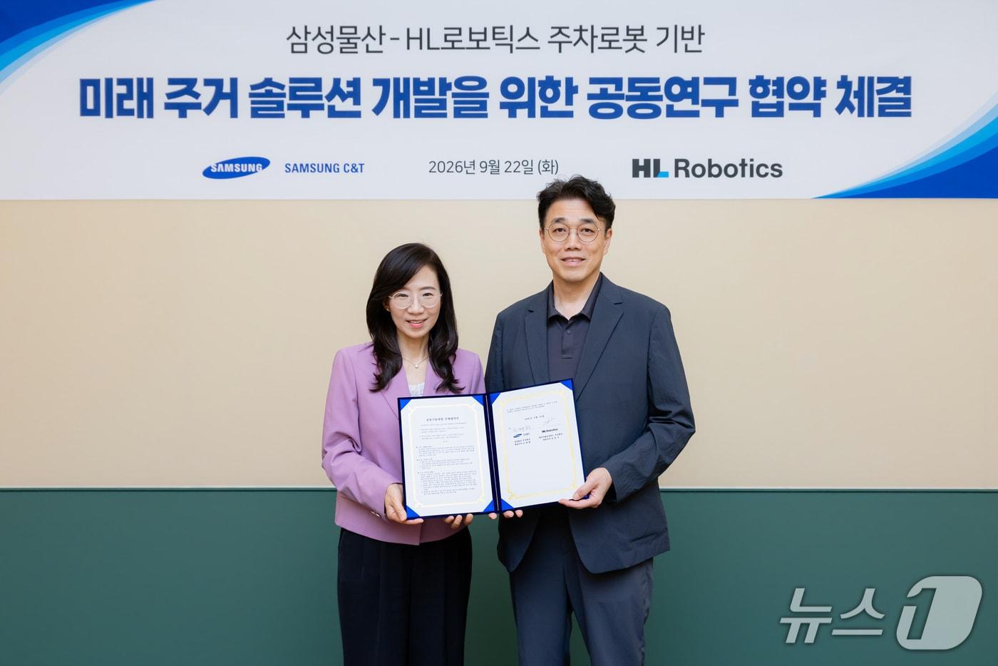 본문 이미지 - 김윤기 HL로보틱스 대표(오른쪽)와 조혜정 삼성물산 부사장(왼쪽)이 22일 서울 송파구 래미안 갤러리에서 열린 자율주행 주차로봇 '파키'(PARKIE) 기반 미래 주거 설루션 개발 업무협약(MOU) 체결식에서 기념 사진을 촬영한 모습(HL로보틱스 제공). 2026.9.22.
