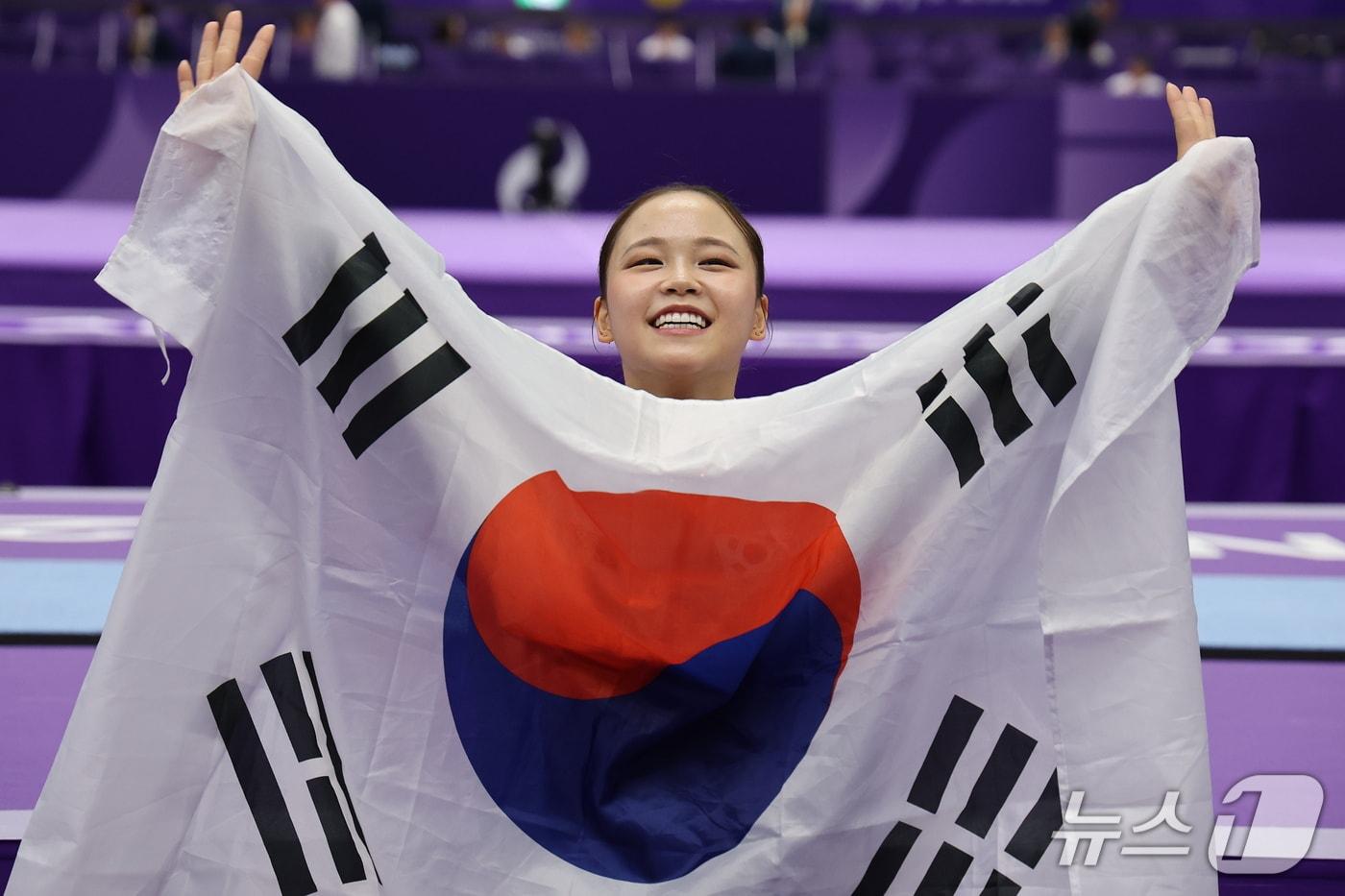 본문 이미지 - 대한민국 여서정이 24일 일본 나고야시 종합체육관에서 열린 2026 아이치·나고야 아시안게임 기계체조 도마 개인전 결선에서 금메달을 획득한 후 태극기들 들고 기뻐하고 있다. 2026.9.24 ⓒ 뉴스1 김도우 기자