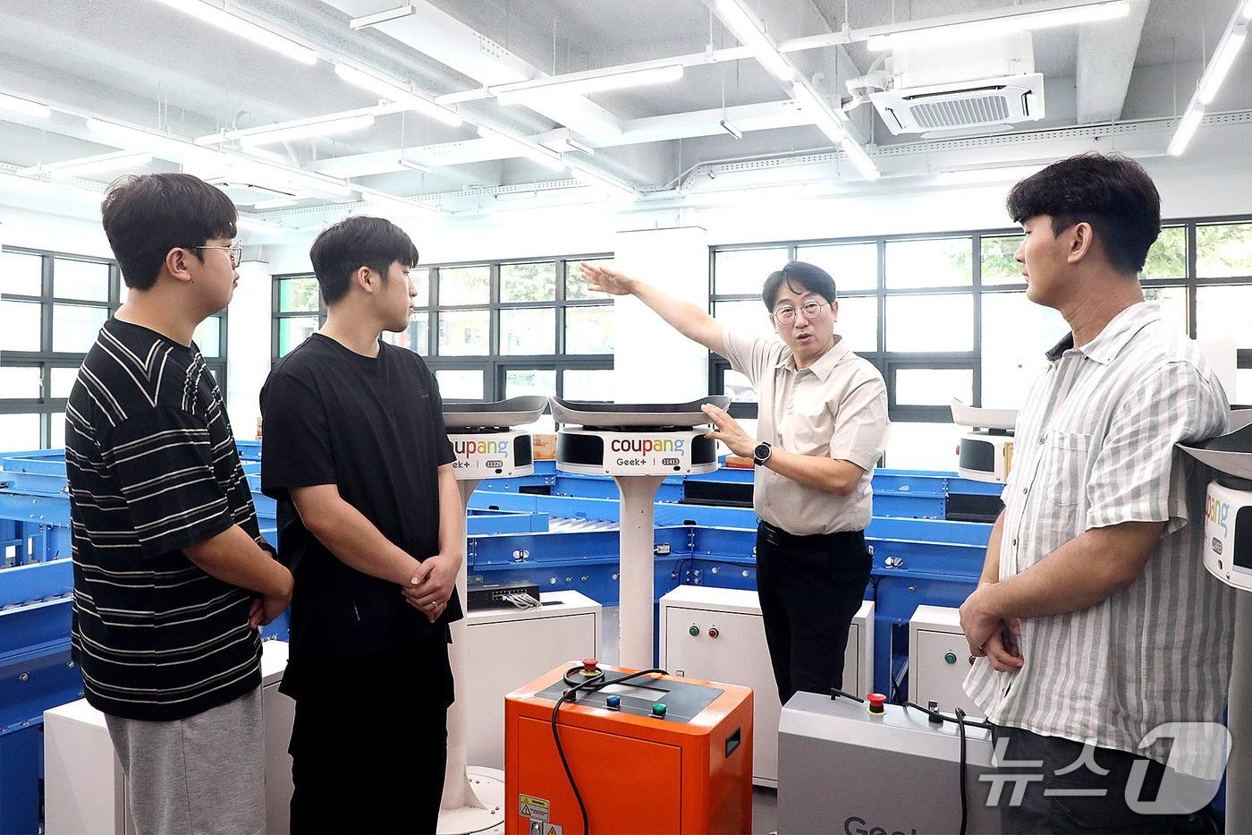 본문 이미지 - 성금길 교수(오른쪽 두번째)가 AI물류교육센터에서 AI 기반 물류자동화 시스템을 설명하고 있다. (영남이공대 제공. 재판매 및 DB 금지)