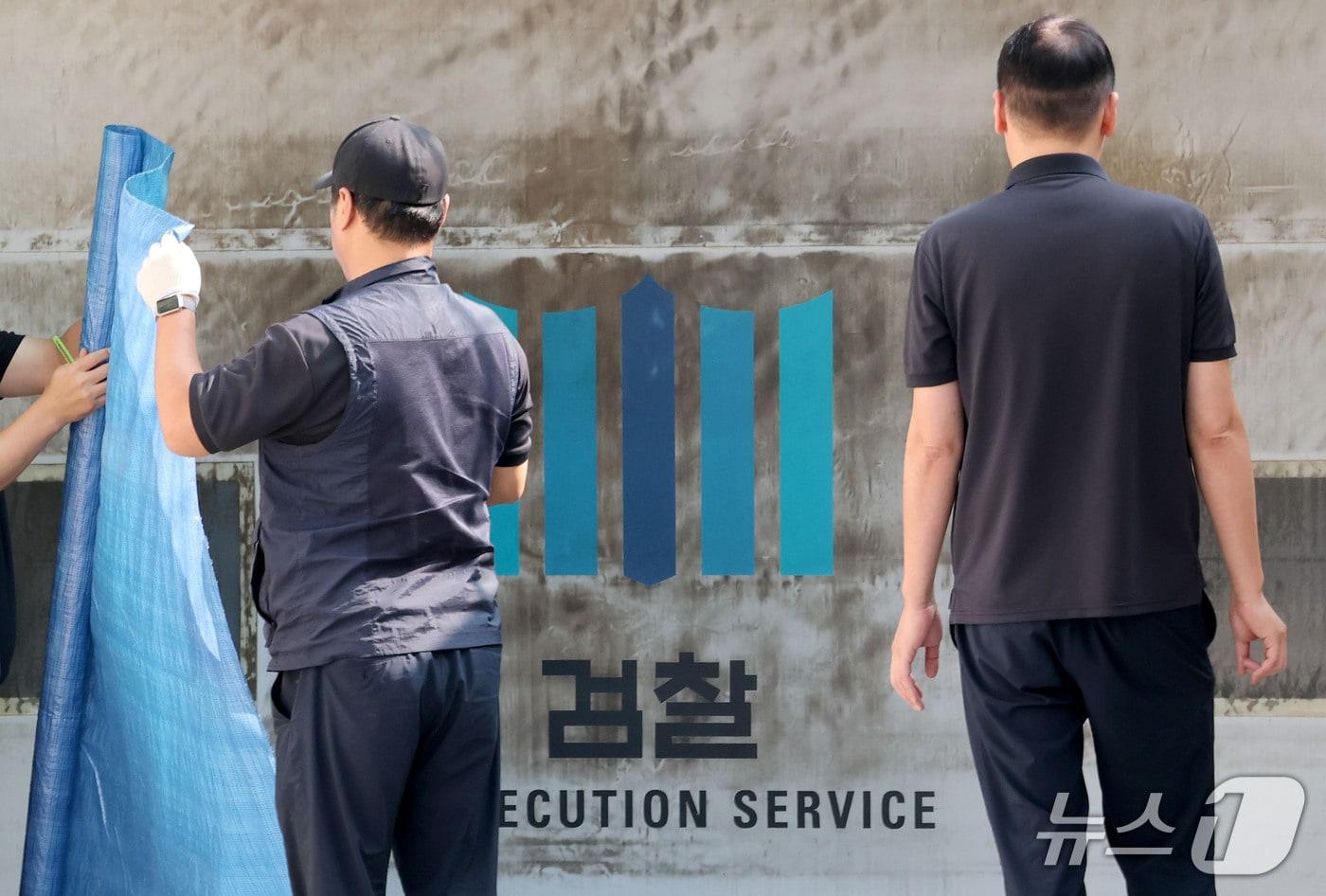 본문 이미지 - 공소청·중대범죄수사청 출범을 이틀 앞둔 30일 서울 서초구 대검찰청에서 관계자들이 주차장 출입문에 새겨진 검찰 표식을 가리기 위한 준비작업을 하고 있다. 2026.9.30 ⓒ 뉴스1 이광호 기자