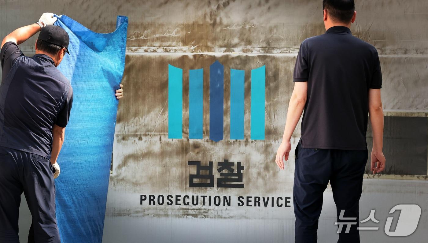 본문 이미지 - 공소청·중대범죄수사청 출범을 이틀 앞둔 30일 서울 서초구 대검찰청에서 관계자들이 주차장 출입문에 새겨진 검찰 표식을 가리기 위한 준비작업을 하고 있다. 2026.9.30 ⓒ 뉴스1 이광호 기자
