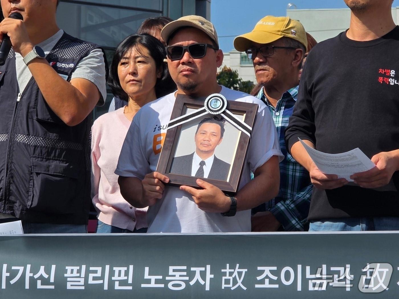 본문 이미지 - 30일 고용노동부 천안지청에서 열린 대원산업 중대재해 진상규명 촉구 기자회견에서 故 조이 칸토 씨의 유족이 영정 사진을 들고 있다./2026.9.30. ⓒ 뉴스1 이시우 기자