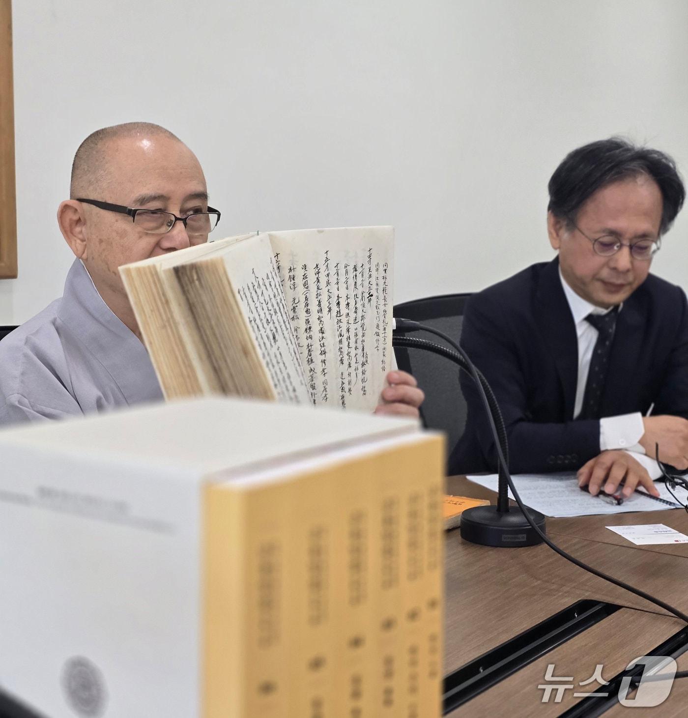 본문 이미지 - 송광사성보박물관장 고정 스님이 7일 서울 대한불교조계종역사박물관에서 금용당 일섭 스님의 연보를 펼쳐 보이고 있다.