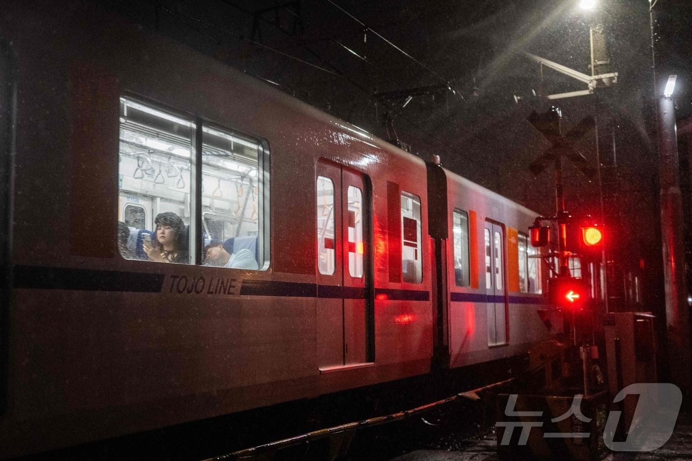 본문 이미지 - 일본 기상청이 도쿄 지역에 폭우를 예보한 6일 도쿄에서 출퇴근하는 사람들이 폭우 속에서 열차를 타고 이동하고 있다. 2026.9.6 ⓒ AFP=뉴스1