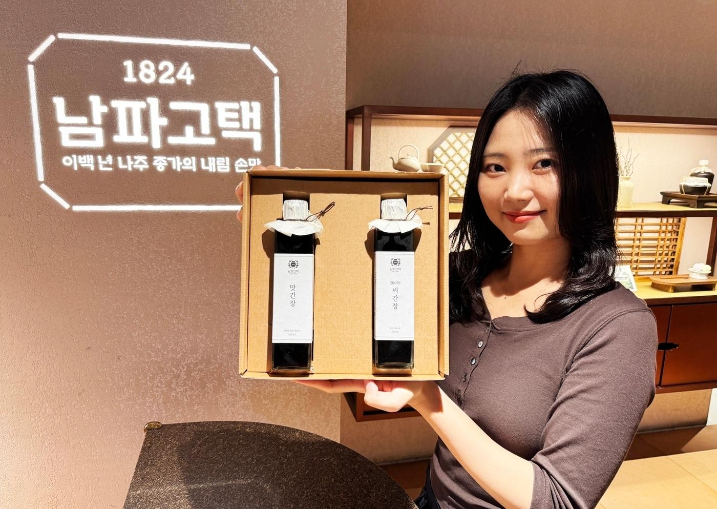 본문 이미지 - 전남 나주 박경중 종가의 대를 이어 내려오는 비결을 담은 '200년 씨간장' 기프트를 선보이고 있는 모델의 모습.(롯데백화점 제공)