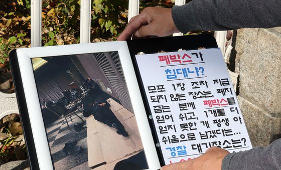 근무복 입고 종이 상자 깔고 취침하는 경찰관의 모습