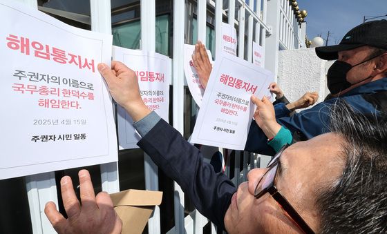 청사 외벽에 한덕수 권한대행 해임통지서 붙이는 시민들