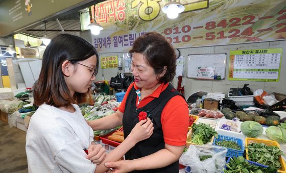 지역 상인에게 카네이션 달아주는 어린이