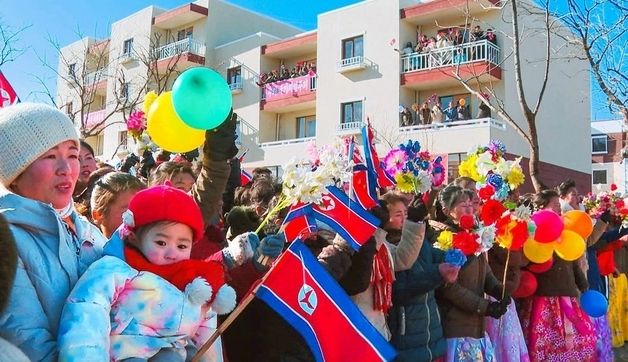새집들이 행사에서 인공기 흔드는 북한 주민들