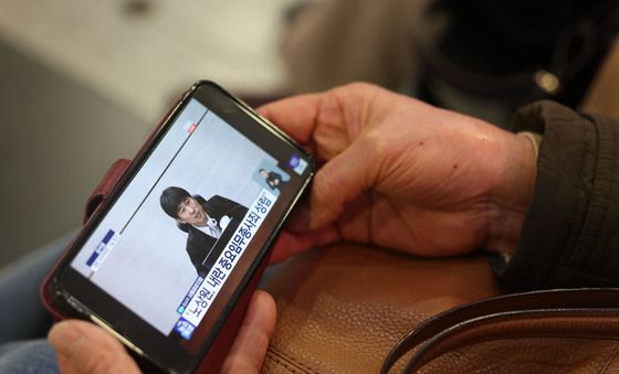 핸드폰으로 윤석열 1심 선고 지켜보는 광주시민